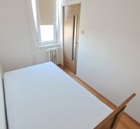 Hálószoba fehér falakkal és fa dekorációjú padlóval egy kétszobás lakásban.