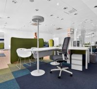 Nyitott ülőhelyekkel rendelkező irodai üzlethelyiség, szőnyeglapok és irodai asztalok.