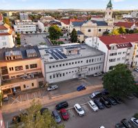 Kilátás M.R. Štefánikra Topoľčanyban üzlethelyiségekkel és templommal a háttérben.