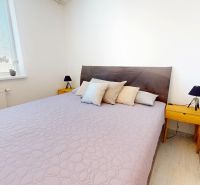 Hálószoba nagy ággyal, éjjeliszekrényekkel és dekoratív párnákkal egy háromszobás lakásban.