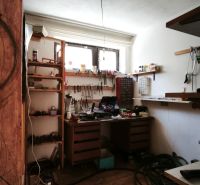 Műhely polcokkal és faasztallal egy családi házban, fa dekoros padlóval.