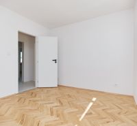 Szoba fehér falakkal, fa dekorációjú padlóval egy háromszobás lakásban.