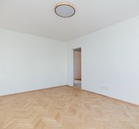 Üres szoba fa dekor padlóval és kilátással a konyhára egy háromszobás lakásban.
