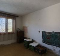 Szoba egy családi házban nagy ablakkal, függönnyel és minimalista berendezéssel.
