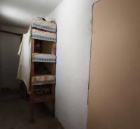 Keskeny folyosó polcokkal egy családi házban, egyszerű berendezés.