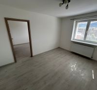 Szoba fa dekorációjú padlóval, fehér falakkal és nagy ablakkal egy háromszobás lakásban.