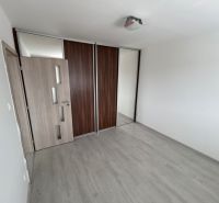 Üres szoba egy háromszobás lakásban, fa dekoros padlóval és beépített szekrénnyel.