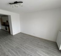 Háromszobás lakás nappalija fa dekor padlóval és bal oldalon konyhával.