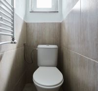 Fürdőszoba a házikóban WC-vel és világos árnyalatú burkolattal.
