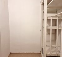 Tárolóhely fehér polcokkal egy kétszobás lakásban, szőnyeggel borított padlóval.