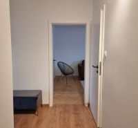 Kétszobás lakás folyosója fa mintás padlóval és kilátással a nappalira.