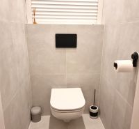 Fürdőszoba egy kétszobás lakásban modern függesztett WC-vel világos csempéken.