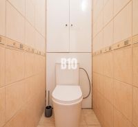 Bézs csempézett WC az egyszobás lakásban, praktikus kialakítás és tárolóhely.