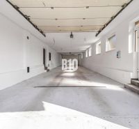Tágas garázs egy családi házban, Nitra városában, több ablakkal és fehér falakkal.