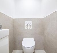Fürdőszoba egy háromszobás lakásban WC-vel és mosdóval, egyszerű csempékkel a falakon.