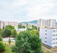 Kilátás egy háromszobás lakásból Nyitrán panelházakra és parkolóra autókkal.