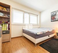 Hálószoba egy családi házban, fa dekoros padlóval és könyvekkel, valamint játékokkal teli polccal.