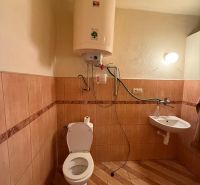 Fürdőszoba WC-vel, vízmelegítő, mosdókagyló, fa dekorációs padló családi házban.