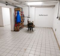 Pincehelyiség csempével, polccal és kabáttal egy családi házban.