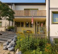 Családi ház Podersdorf am See-ben kőlépcsőkkel és virágokkal teli kerttel.