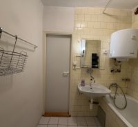 Fürdőszoba egy háromszobás lakásban mosdóval, káddal és a falon lévő vízmelegítővel.