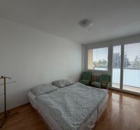 Hálószoba egy háromszobás lakásban, fa dekor padlóval, ággyal és székekkel.