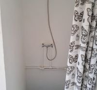 Zuhanykabin fehér függönnyel, pillangómintával a házikóban.