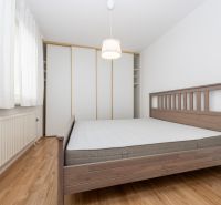 Hálószoba egy háromszobás lakásban, fa ággyal és fa dekorációjú padlóval.