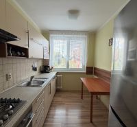 Konyha egy háromszobás lakásban fa dekor padlóval és konyhabútorral.