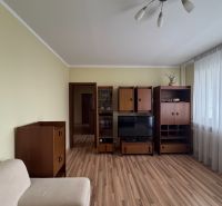 Nappali egy háromszobás lakásban, fa dekorációjú bútorokkal és padlóval.