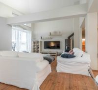 Nyaraló apartman fehér kanapékkal és fa dekorációjú padlóval, világos környezet.