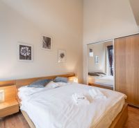 Hálószoba ággyal és fa dekorációjú padlóval egy üdülő apartmanban.