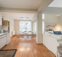 Rekreációs apartman fa dekorációjú padlóval, konyhával, étkezőasztallal és kényelmes ülőhellyel.