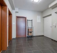 A nyaraló apartman előcsarnoka sötét padlólappal, faajtókkal és fogassal.