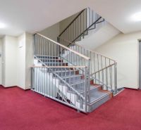 Folyosó a Rekreációs apartmanban piros szőnyeggel, lépcsőházzal és lifttel.