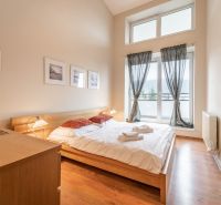 Világos hálószoba franciaággyal és fa dekorációjú padlóval egy nyaraló apartmanban.