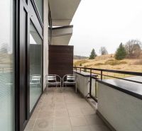 Rekreációs apartman erkélye Donovalyban, kilátással a természetre és a házakra.
