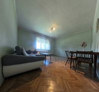 Nappali egy családi házban kanapéval, asztallal és fa dekorációjú padlóval.