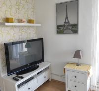 Nappali egy kétszobás lakásban világos bútorokkal és Eiffel-torony dekorációval.