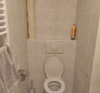 Fürdőszoba WC-vel, papírtartóval és törölközőtartóval egy kétszobás lakásban.