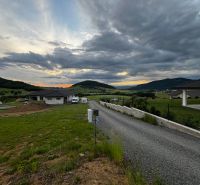 Stožok község panorámája naplementével és lakóterületekkel a dombos vidéken.