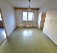 Tágas szoba ablakkal, csempézett falakkal és padlóval egy családi házban.