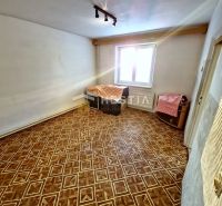 Szoba egy családi házban fa dekorációjú padlóval, fehér falakkal és ablakkal.