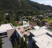 Kilátás egy tetőteraszra az épületek között, amelyeket természet vesz körül Rajecké Teplicében, az M. R. Štefánika utcában.