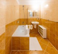 Fürdőszoba a nyaraló apartmanban káddal, mosdóval és világos csempékkel.