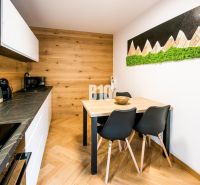 Nyaraló apartman belső tere konyhával, étkezőasztallal és fa dekorációjú padlóval.