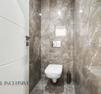Fürdőszobai WC függesztett toalettel és márványfalakkal egy háromszobás lakásban.