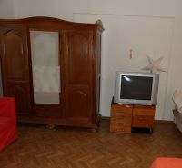 Szoba egy kétszobás lakásban fa bútorokkal és fa dekorációjú padlóval.
