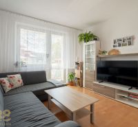 Nappali egy háromszobás lakásban kanapéval, televízióval és fa dekorációjú padlóval.