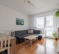 Világos nappali egy háromszobás lakásban, fa dekorációjú padlóval és kanapéval.